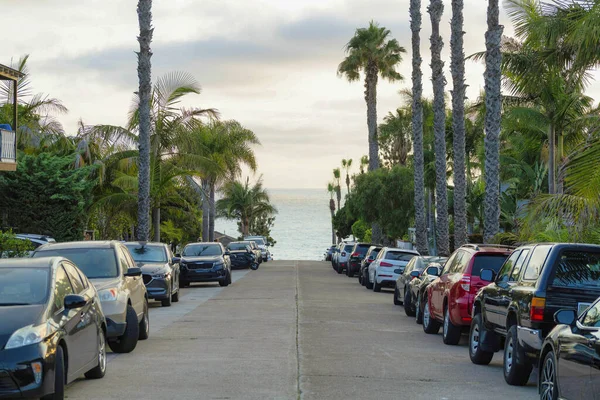 両側に駐車車と海岸に傾いてまっすぐアスファルトの道路の景色 — ストック写真
