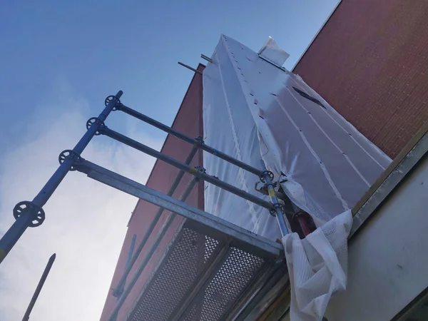 背景に高い赤い壁と青い空を持つ建設現場の低角度ショット — ストック写真