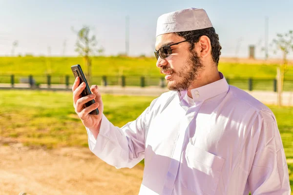 Arabisk Man Traditionell Trasa Kollar Sin Mobiltelefon Parken — Stockfoto