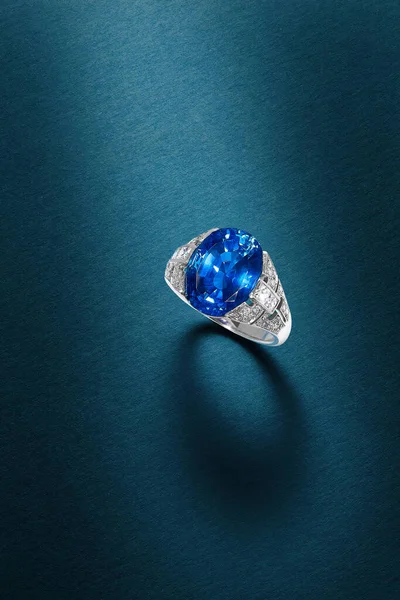 A vertical shot of a beautiful ring with a precious blue gem on a blue surface