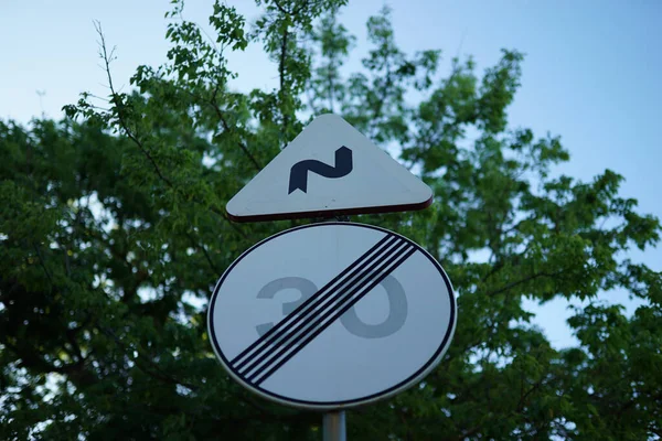 青い空と葉を背景にした道路標識 — ストック写真