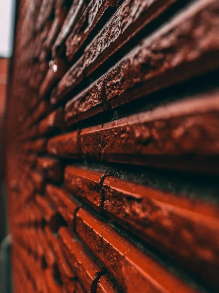 背景がぼやけているラフな質感の赤レンガの壁の垂直ショット — ストック写真
