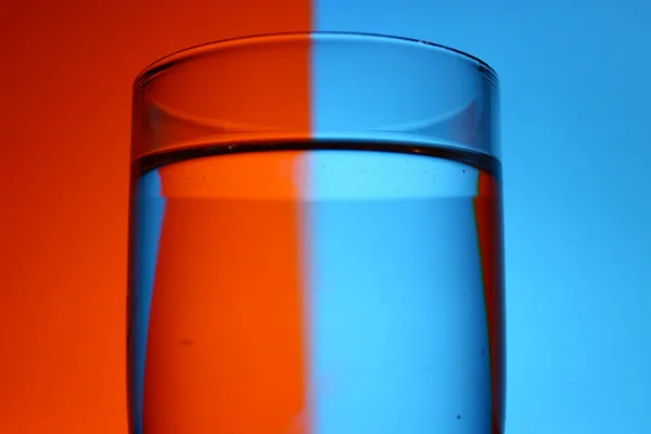 Close Copo Água Contra Fundo Vermelho Azul Embaçado — Fotografia de Stock
