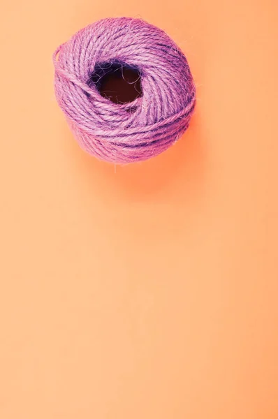 コピースペース付きオレンジの背景にウールの単一の柔らかい紫色のテキスタイルボールのトップビュー — ストック写真
