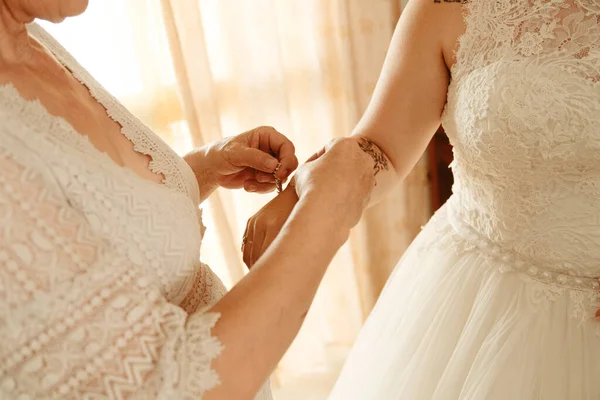 The mother of bride helping her daughter to get ready