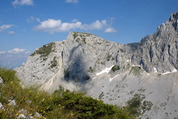 青空の下近くに草や植物が茂る岩山 — ストック写真