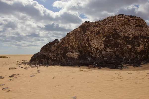 Uma Grande Rocha Marrom Escuro Praia Areia Sob Céu Brilhante — Fotografia de Stock