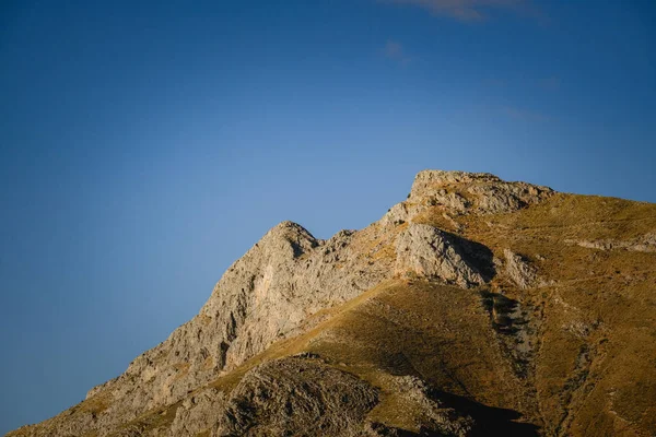 Una Montagna Rocciosa Con Erba Sopra Sotto Cielo Blu — Foto Stock