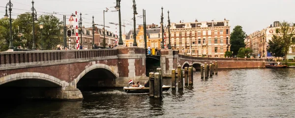 建物がある茶色のアーチ型の橋の下の運河 — ストック写真