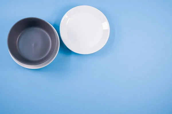 蓝色背景上空白的陶瓷 白色和黑色盘子的顶部视图 — 图库照片