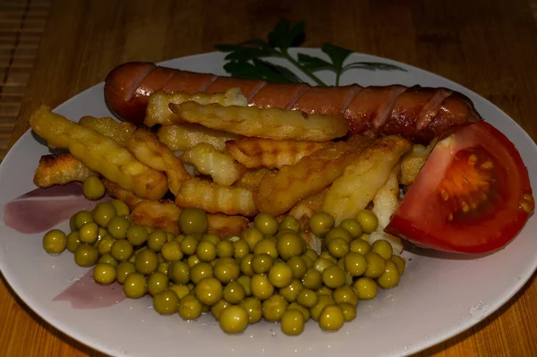 Uma Salsicha Com Batatas Fritas Ervilhas Verdes Tomate Fatiado Prato — Fotografia de Stock