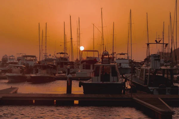 ボートがある港の近くの美しい明るいオレンジ色の夕日 — ストック写真