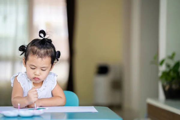 一个亚洲小女孩在屋里的桌子旁玩耍 — 图库照片