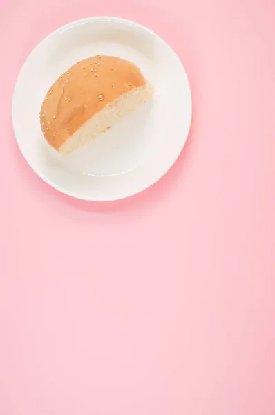 ピンクの背景にパンの半分の垂直ショット — ストック写真