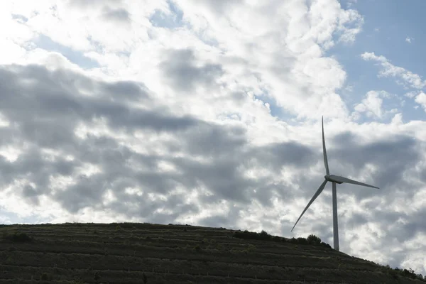 Nízký Úhel Záběru Větrné Turbíny Vrcholu Kopce Zachyceného Zatažený Den — Stock fotografie
