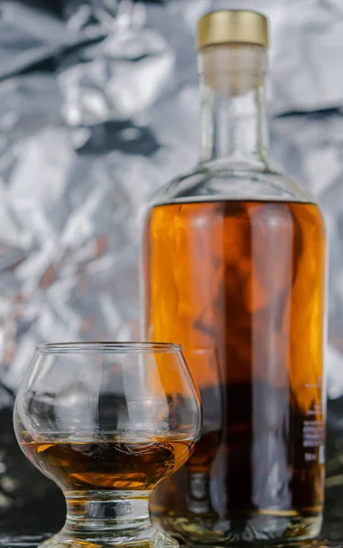 テーブルの上のガラスの横にあるウイスキーのボトル — ストック写真