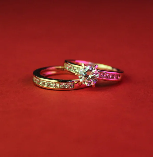 Nahaufnahme Zweier Goldener Verlobungsringe Mit Diamanten Auf Roter Oberfläche — Stockfoto