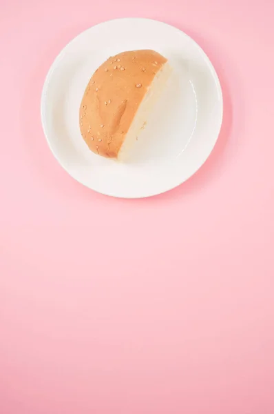 ピンクの背景に隔離された皿の上にパンパンの半分の垂直ショット — ストック写真