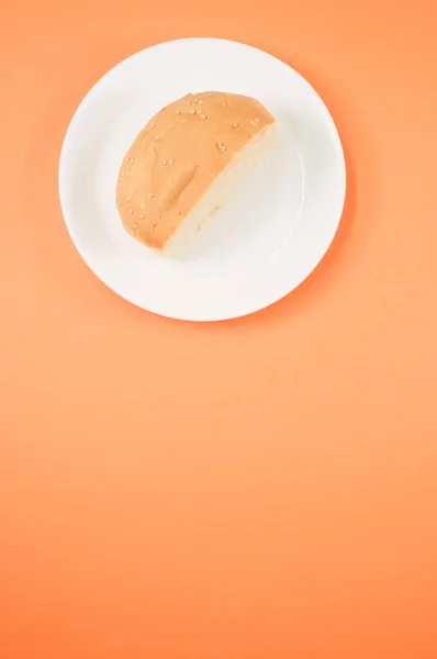 Вертикальний Знімок Наполовину Хлібної Булочки Тарілці Ізольовано Світло Оранжевому Фоні — стокове фото