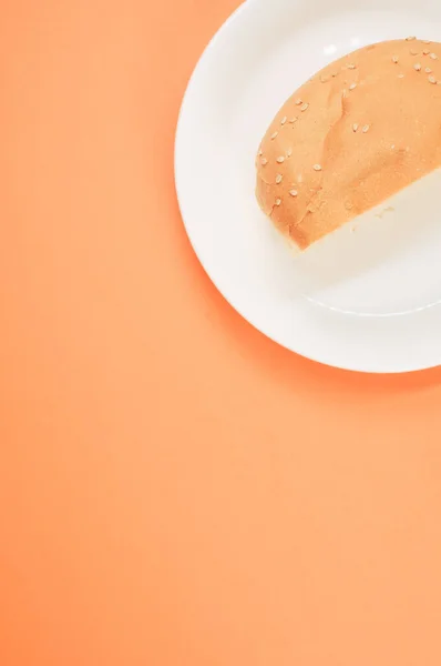 Вертикальный Снимок Полухлебной Булочки Тарелке Изолированной Светлом Оранжевом Фоне — стоковое фото