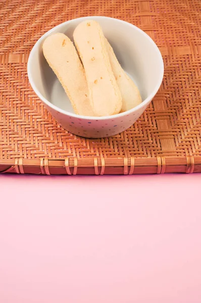 Вертикальний Знімок Леді Палець Печива Бамбуковому Плетеному Лотку Ізольовано Рожевому — стокове фото