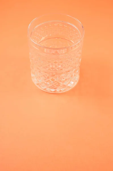 Een Verticaal Shot Van Kristalglas Geïsoleerd Een Oranje Achtergrond — Stockfoto