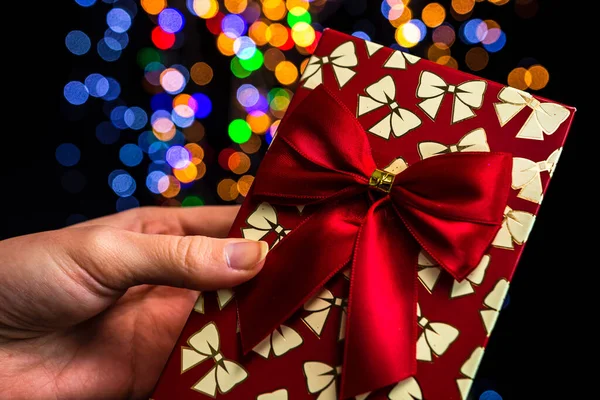 Una Mano Sosteniendo Caja Regalo Navidad Roja Contra Coloridas Luces —  Fotos de Stock