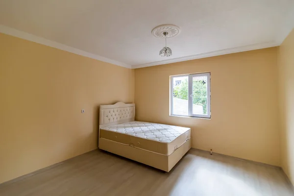 Sarı Boş Bir Odada Bir Yatak Bir Avize — Stok fotoğraf