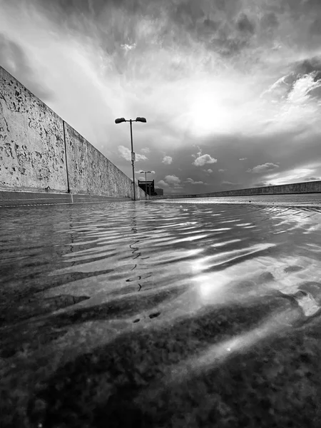 Een Verticaal Grijswaarden Shot Van Een Waterplas Met Een Betonnen — Stockfoto