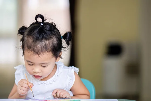 一个泰国可爱的小女孩在桌旁的纸上画画 — 图库照片