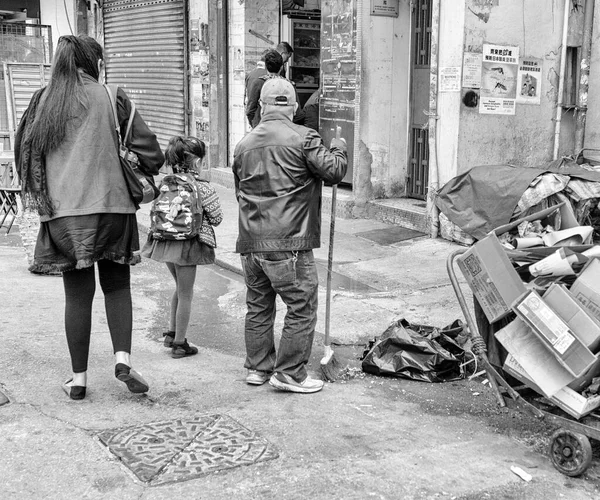 2018年12月22日 一名清洁工人在香港街上拿着扫帚 妇女和女儿走过的灰白色照片 — 图库照片