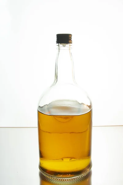 明るい背景のテーブルの上に琥珀色のウイスキーのボトル — ストック写真