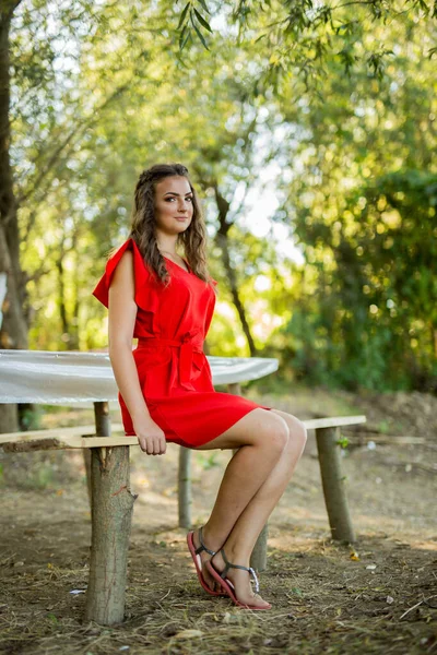 赤いドレスのベンチに座っている若い女性の浅い焦点のショット — ストック写真