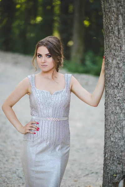 Gümüş Bir Elbiseyle Ağaca Yaslanan Genç Bir Kadının Sığ Odak — Stok fotoğraf