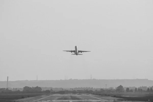 一张从机场起飞的飞机的灰度照片 — 图库照片