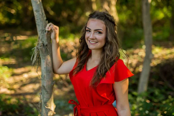 一个穿着红色衣服靠在树上的时髦女人的肤浅的特写镜头 — 图库照片