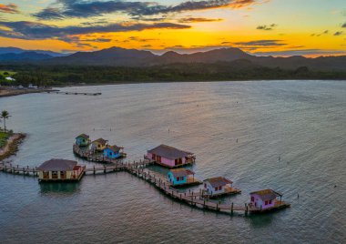A landscape of cottages and docks on the sea during the sunset in Maimon Bay, Puerto Plata, the Dominican Republic clipart