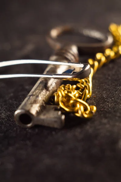 Een Oude Sleutel Met Een Gouden Ketting Een Getextureerd Oppervlak — Stockfoto