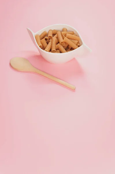 Vertikal Bild Skål Med Okokt Pasta Och Träsked Rosa Yta — Stockfoto