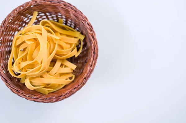 Eine Draufsicht Auf Ungekochte Fettuccine Pasta Auf Einer Weidenschüssel Isoliert — Stockfoto