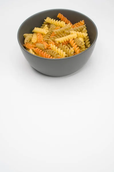 在一个白色背景隔离的碗上垂直拍摄三色的罗蒂尼面食 — 图库照片