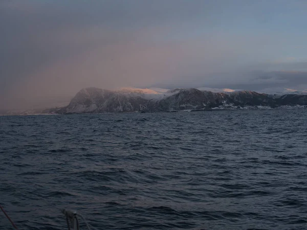 日の出の海の水に囲まれた雪の山の美しいショット — ストック写真