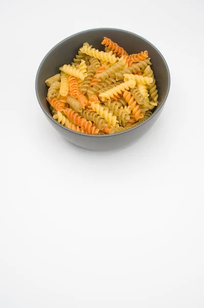 在一个白色背景隔离的碗上垂直拍摄三色的罗蒂尼面食 — 图库照片