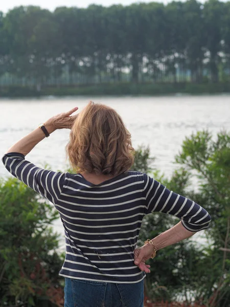 stock image A Caucasian senior woman wearing a striped shirt and denim pants in a park