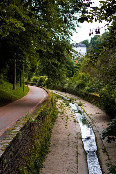 歩道に沿って村を流れる狭い小川 — ストック写真