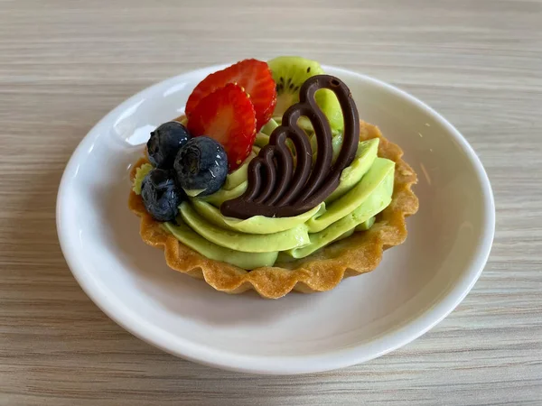 新鮮な果物とチョコレートの装飾が施されたおいしいピスタチオクリームタルトのクローズアップ — ストック写真