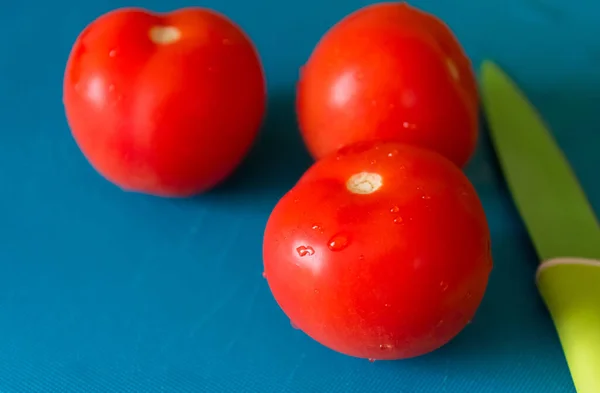 Drei Frische Kirschtomaten Und Ein Messer Auf Blauem Hintergrund — Stockfoto