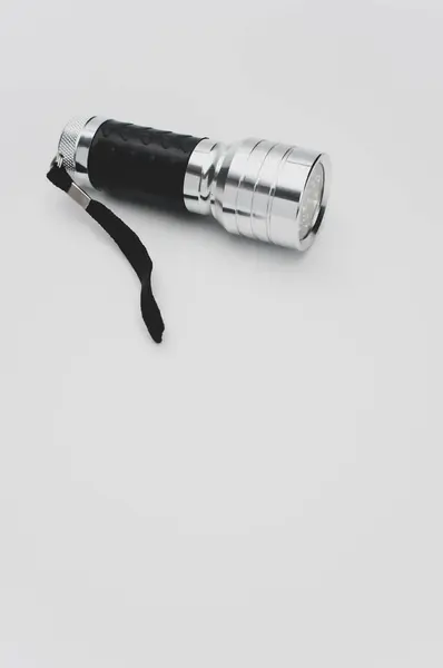 白い背景に孤立した小さな黒い銀の懐中電灯の垂直ショット — ストック写真