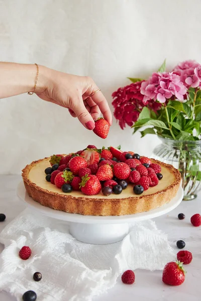 Eine Frau Legt Eine Erdbeere Auf Einen Leckeren Käsekuchen Auf — Stockfoto