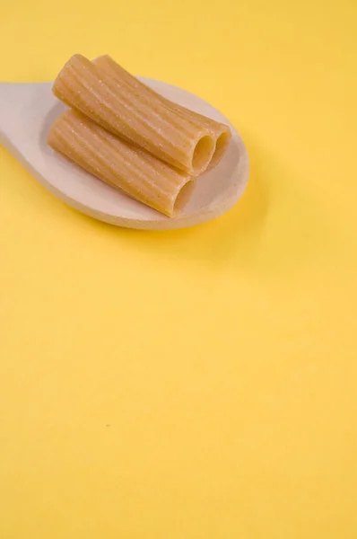 白い鉢に縦に切ったリガトーニと黄色い面にスプーンを脇に置き テキスト用の空きスペースがある — ストック写真